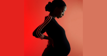 Pregnant black woman in shadow on a red background