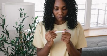 Black woman looks at the result of a home pregnancy test