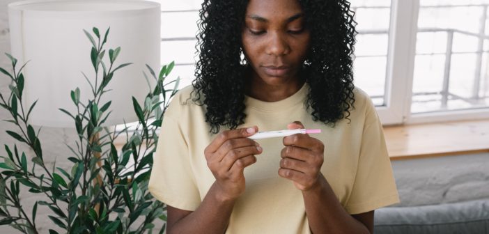 Black woman looks at the result of a home pregnancy test